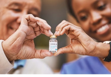 2 medical professionals making a heart symbol with their hands with some skin medicine in the middle