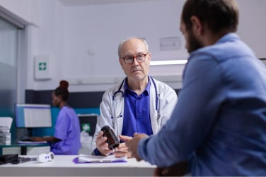 medic showing a bottle of pills to a patient at an examination